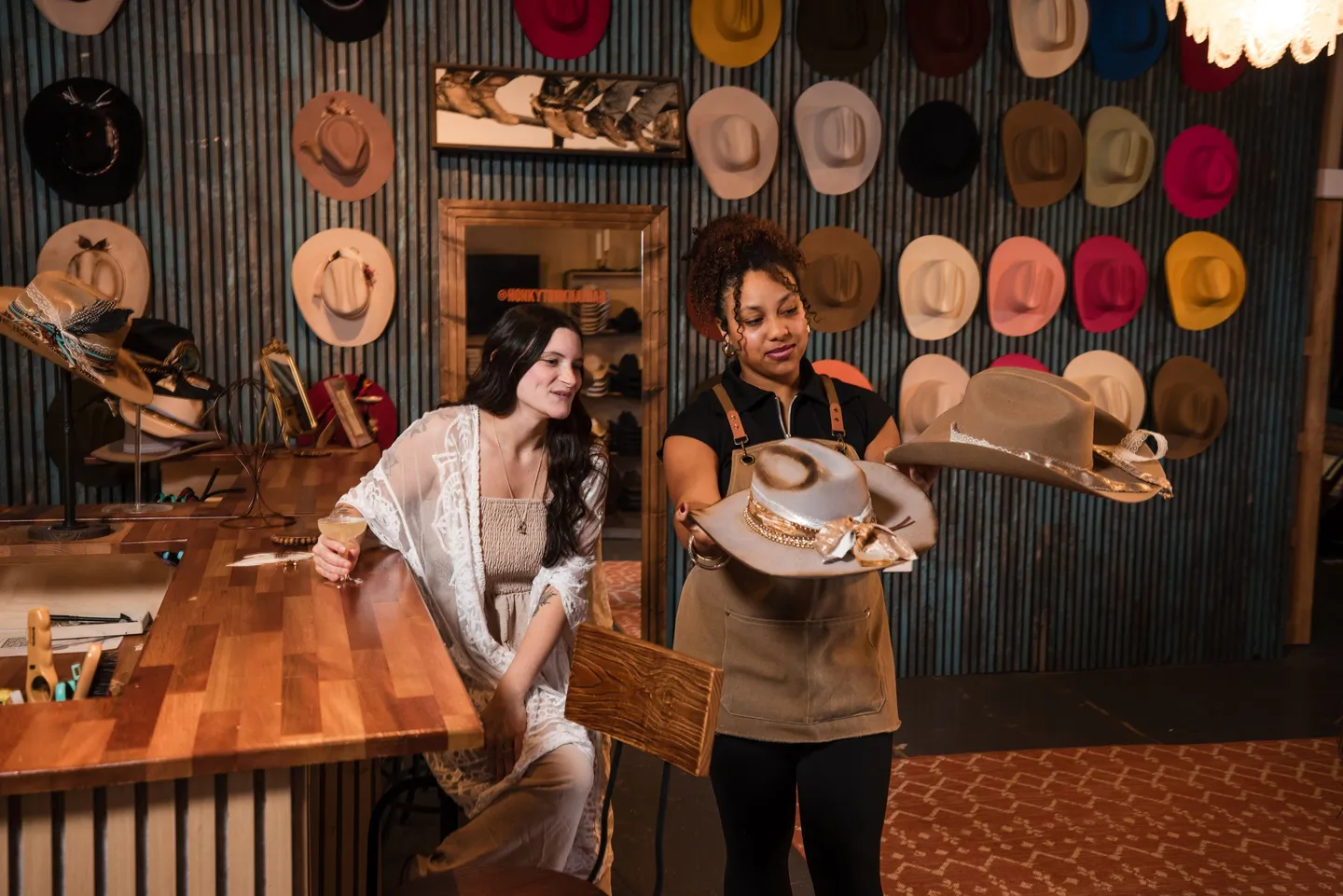 A Honky Tonk Hat Bar team member helping a guest choose a cowboy hat
