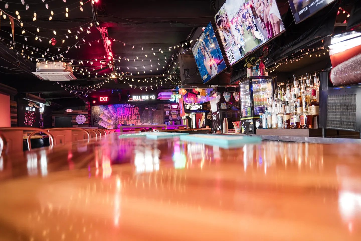 A group table facing TVs inside Honky Tonk Hideaway